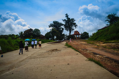 Rear view of people walking on road against sky