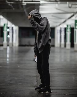 Full length of man wearing hooded jacket while holding in parking lot