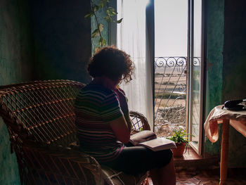 Woman reading book while sitting at home