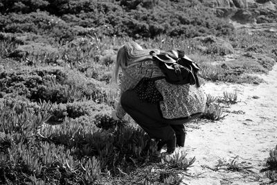 Woman plucking plant on field while hiking
