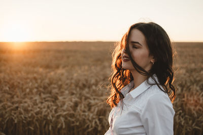 Woman standing on land against sky during sunset