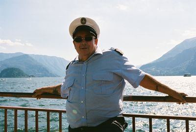 Man standing by railing against mountain and sky