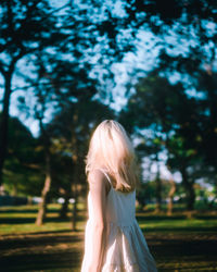 Rear view of woman standing against trees