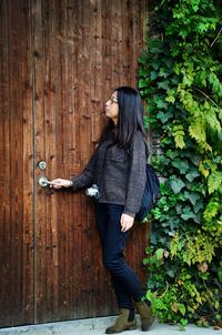 Young woman opening wooden door