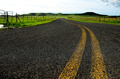 Surface level of road amidst land against sky