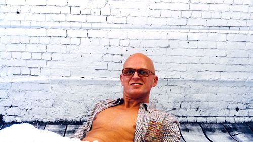 Portrait of man wearing sunglasses against wall