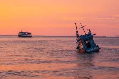 Sailboat in sea against sky during sunset