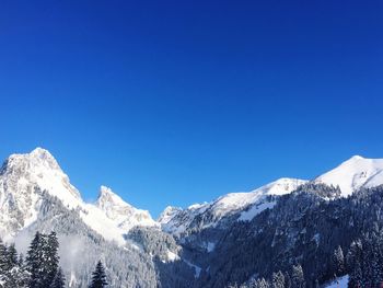 Snowcapped mountains against clear blue sky