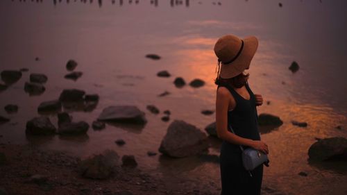 High angle view of woman standing on shore at beach during sunset