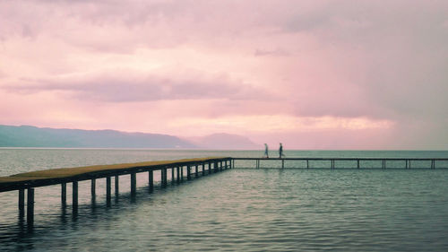 Pier over sea against sky during sunset