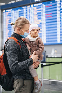 Man and girl watching timetable information at the airport, passengers waiting for a plane. family