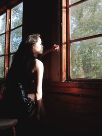 Woman looking through window at home