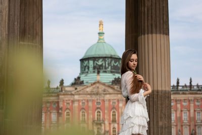 Portrait of woman standing against church in city