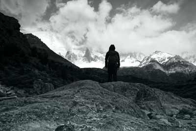 Rear view of man standing on mountain against sky