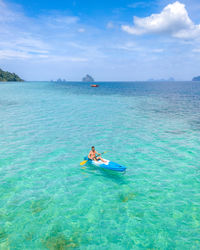 Man kayaking in sea against sky