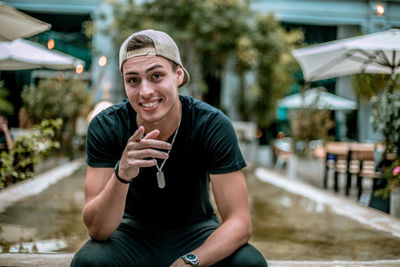 Portrait of happy young man pointing while sitting outdoors