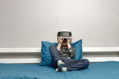 Portrait of boy sitting on bed at home