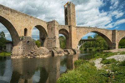 Arch bridge over river against sky