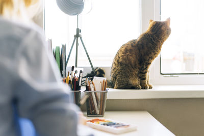 Young woman with red hair illustrator artist draws at desk at home