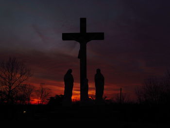 Silhouette cross against dramatic sky during sunset