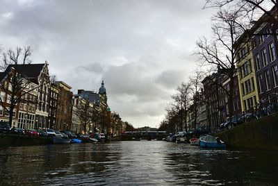 Canal amidst buildings in city against sky