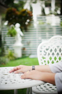 Cropped hands of woman sitting at table in yard