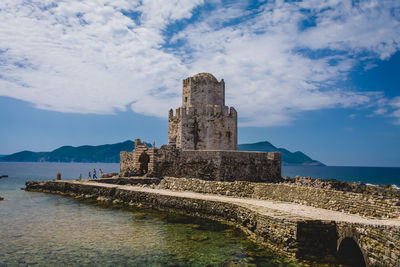 Old building by sea against sky