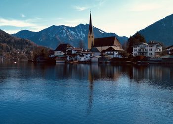 Buildings by lake against sky