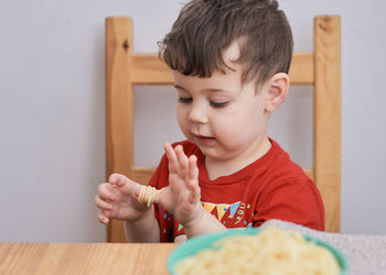 Cute boy is playing with his pasta at lunch time