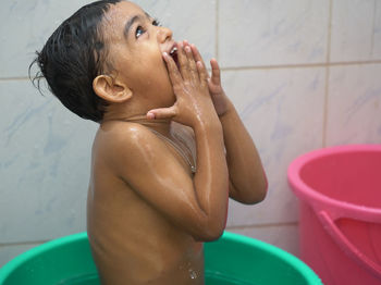 Shirtless boy taking bath in bathroom