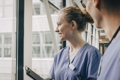 Smiling female nurse looking through window at hospital