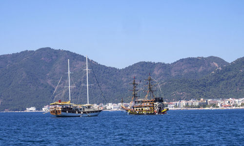 Yachts sailing on aegean sea against clear blue sky