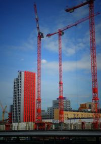 Red cranes at construction site against sky