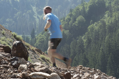 Side view of man on rock in forest