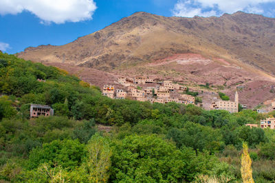 Trees and houses on mountain against sky