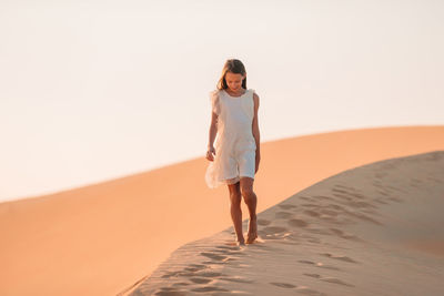 Full length of woman standing on sand dune