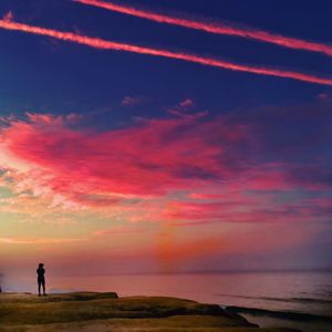 Silhouette man on beach against sky during sunset