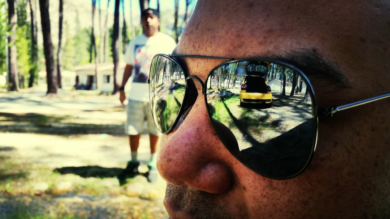 lifestyles, leisure activity, focus on foreground, water, reflection, tree, men, part of, close-up, day, person, selective focus, holding, unrecognizable person, incidental people, outdoors, sunglasses