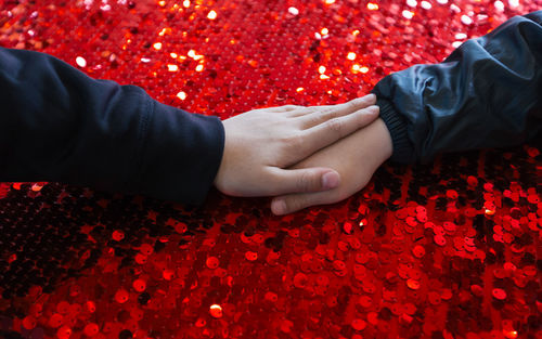 Cropped hands of children on red glitters