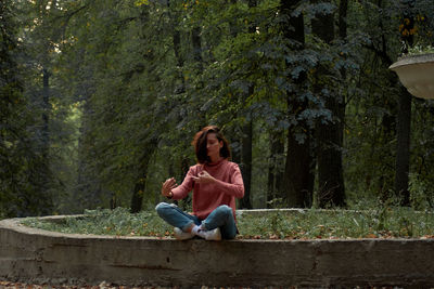 A woman in casual clothes does yoga in an old park