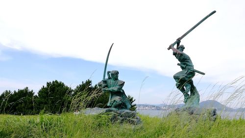 Statues on field against sky