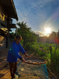 Full length of man standing in yard against sky at sunset