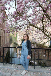 Smiling beautiful young girl stands on the old bridge under blossoming trees