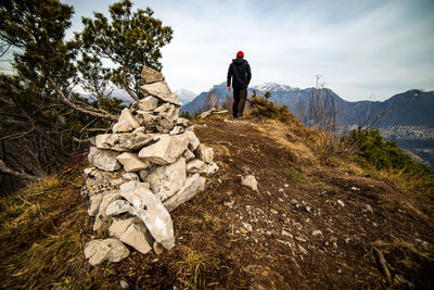 Rear view of man standing on rock against sky