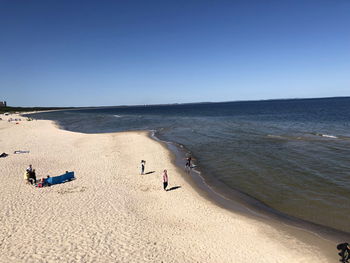 People on beach against clear sky