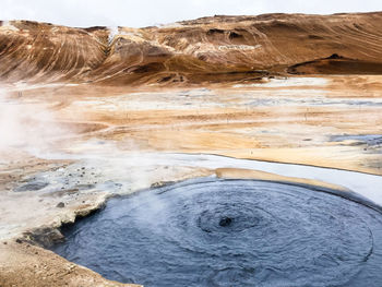 A bubbeling hot spring surrounded with rocks and sand in hverir, iceland