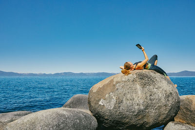 Young woman laying by lake tahoe reading a kindle book during the day