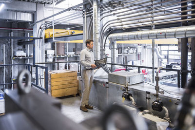 Man with docuents looking on factory shop floor