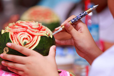 Close-up of hands making art on watermelon