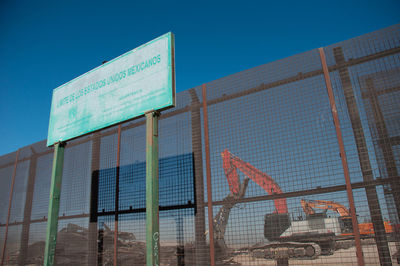 Low angle view of information sign against clear blue sky